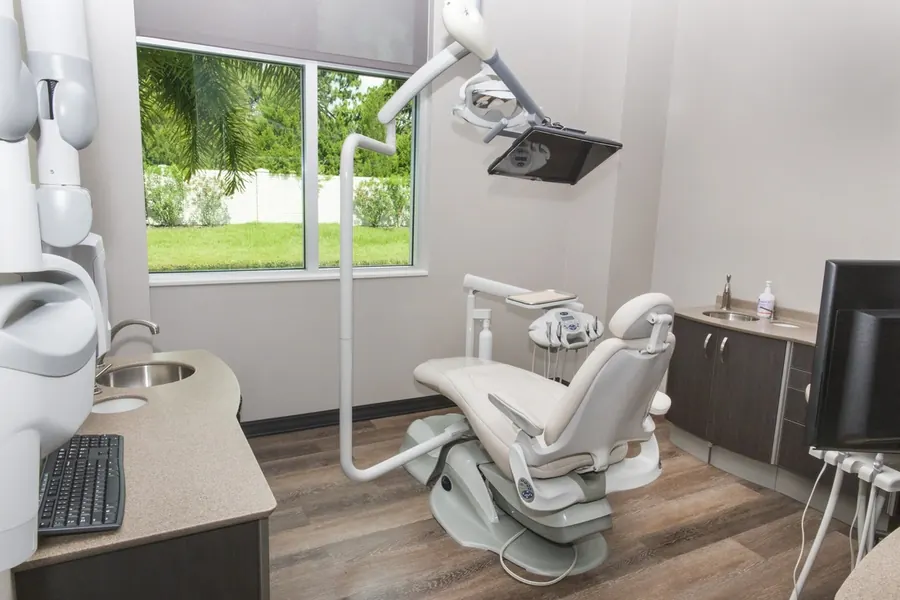 A bright treatment room at Tindal Prosthodontics with windows onto greenery.