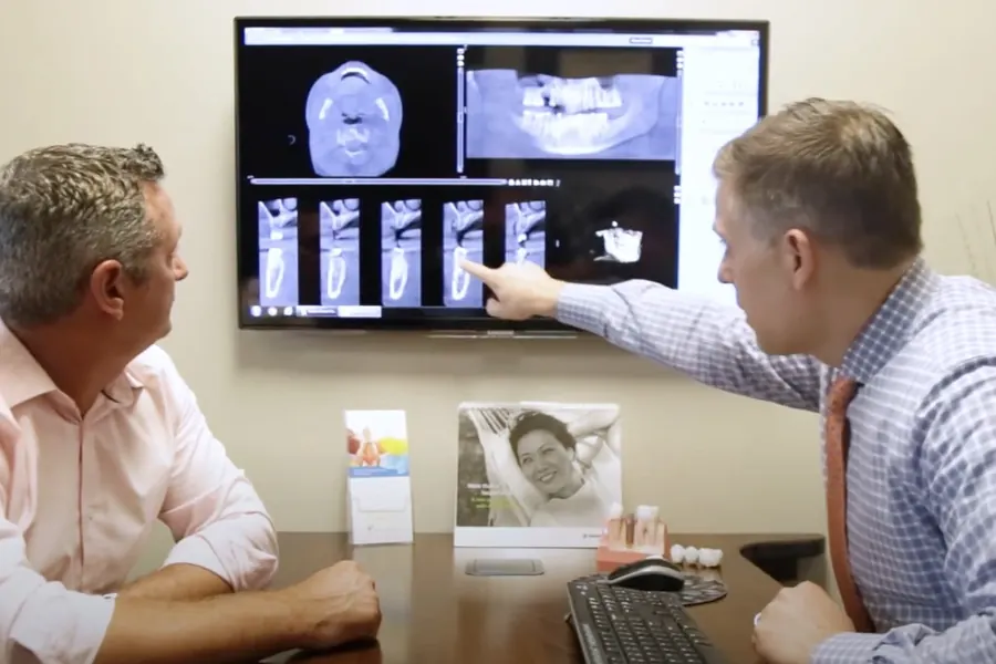 Dr. Ben Tindal explaining x-rays on a screen to a patient.